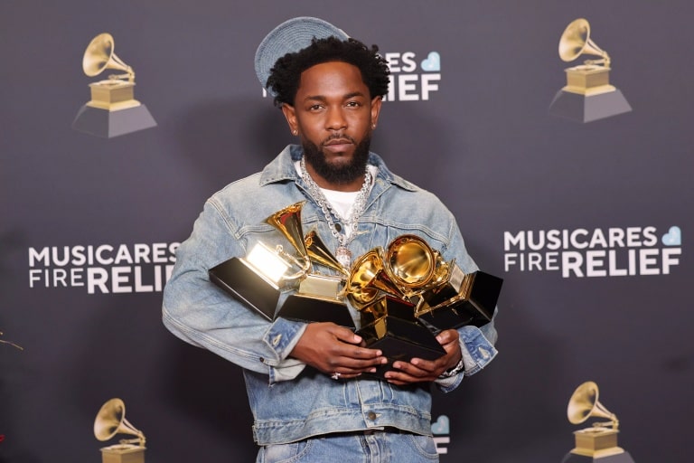 kendrick lamar holds multiple grammy awards in his hands